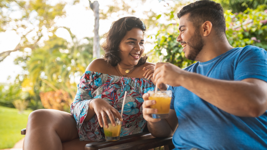 Couple portant des vêtements estivaux et sirotant un cocktail durant ses vacances. 