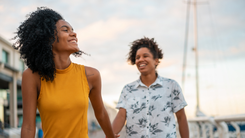 Couple se tenant par la main et souriant lors d’une escapade. 