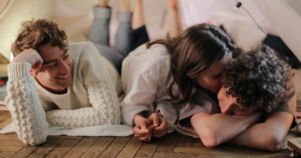 Polyamorous people laying on the floor together.