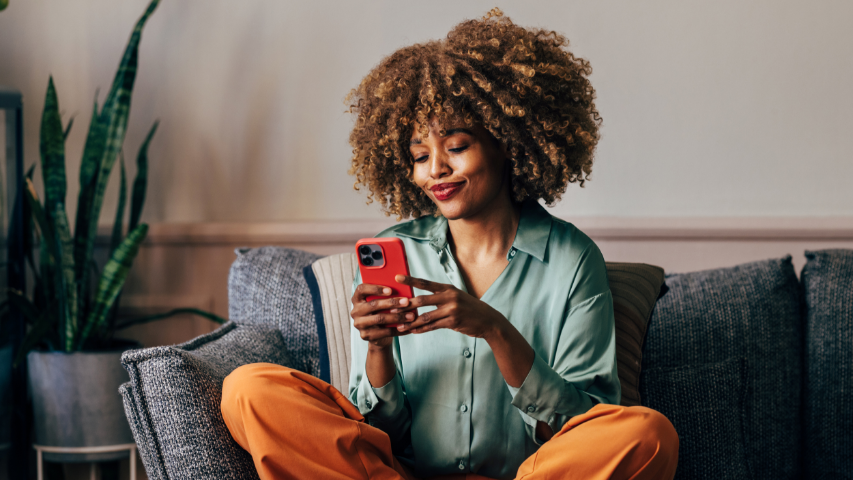 Woman smirking on her sofa while looking through her sexts.