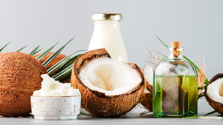 Various coconut-based products including a cracked open coconut, coconut oil, and coconut butter.