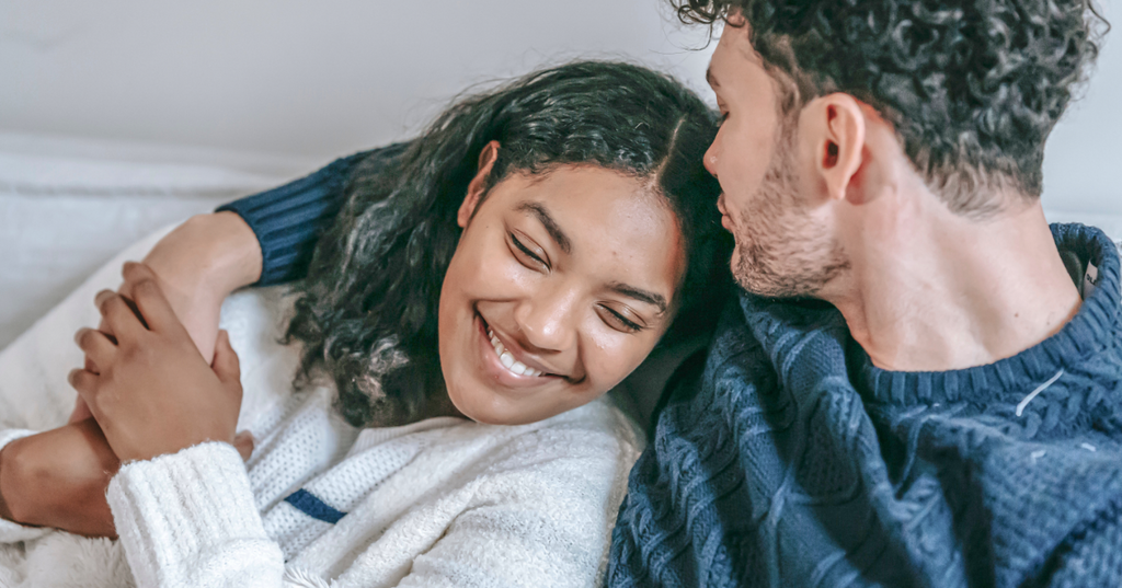 L'homme embrasse le haut de la tête de la femme alors qu'ils se tiennent de près.