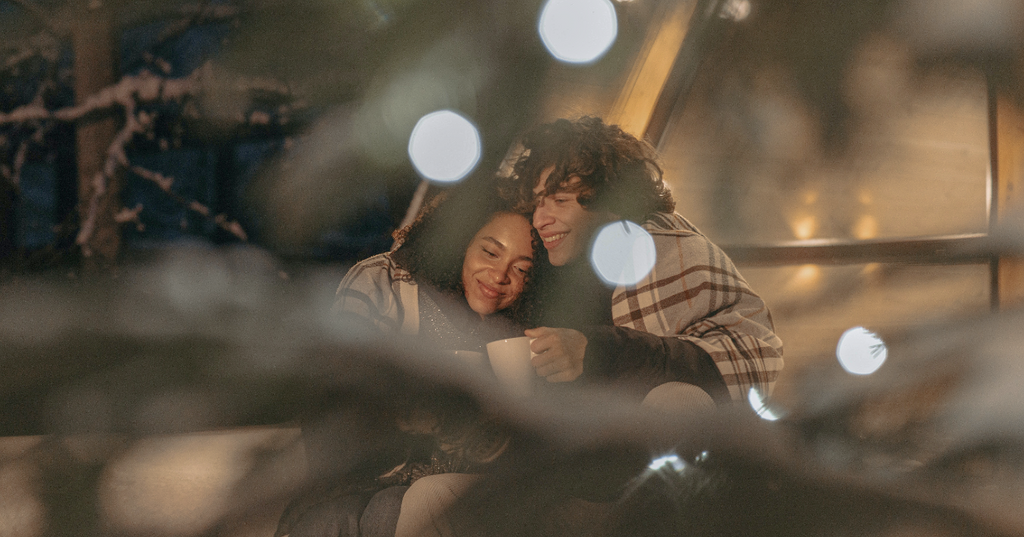 Two people wrapped up in blankets cuddling each other on a cold night.