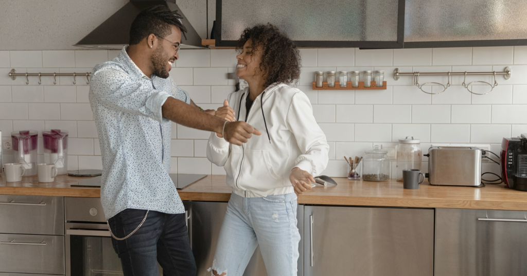Two people dancing around in their kitchen.