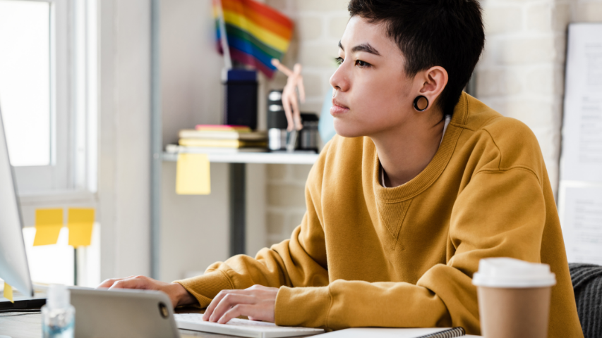Une personne portant des espaceurs aux oreilles est assise à son bureau et fait une recherche en ligne sur l’éducation sexuelle au Canada. 