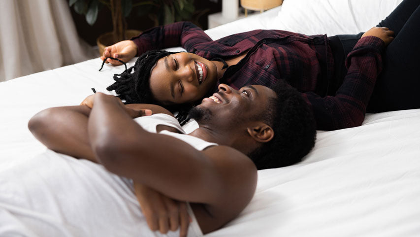 Un couple qui rit ensemble au lit après avoir discuté des frouts.