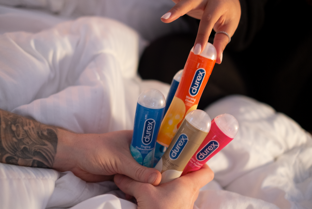 A hand pulls out Durex Warming Lubricant from an array of Durex lube options.