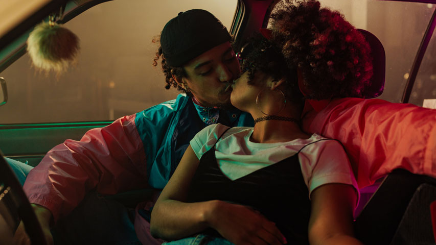 Young couple kissing in their roomy, vintage car.