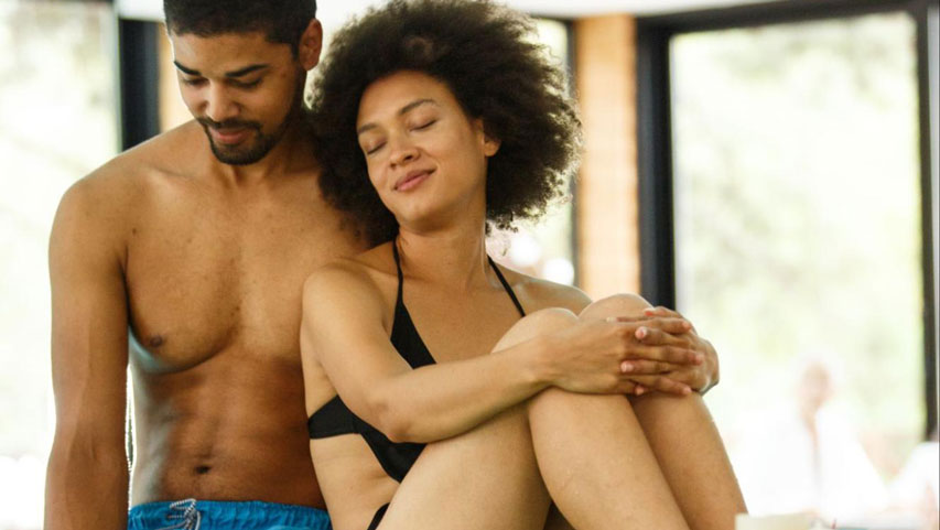 Two partners hanging out on the edge of an indoor hot tub.