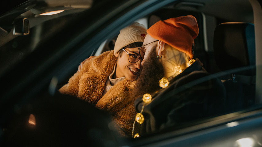 Two people in beanies cuddle up closer together in the driver and passenger seats.