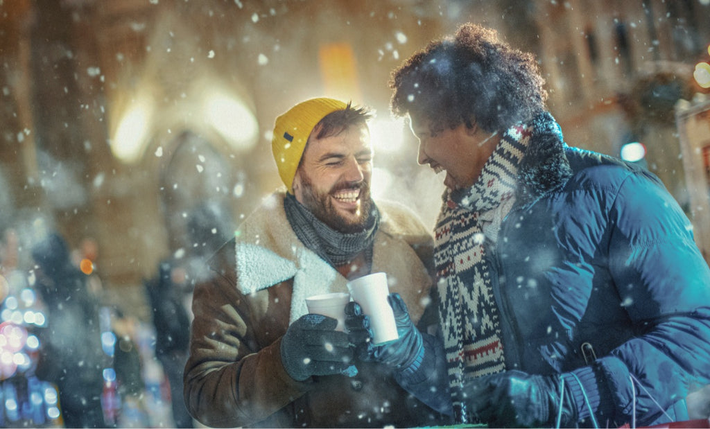 Deux hommes partagent un breuvage chaud sous la neige, un soir d’hiver.