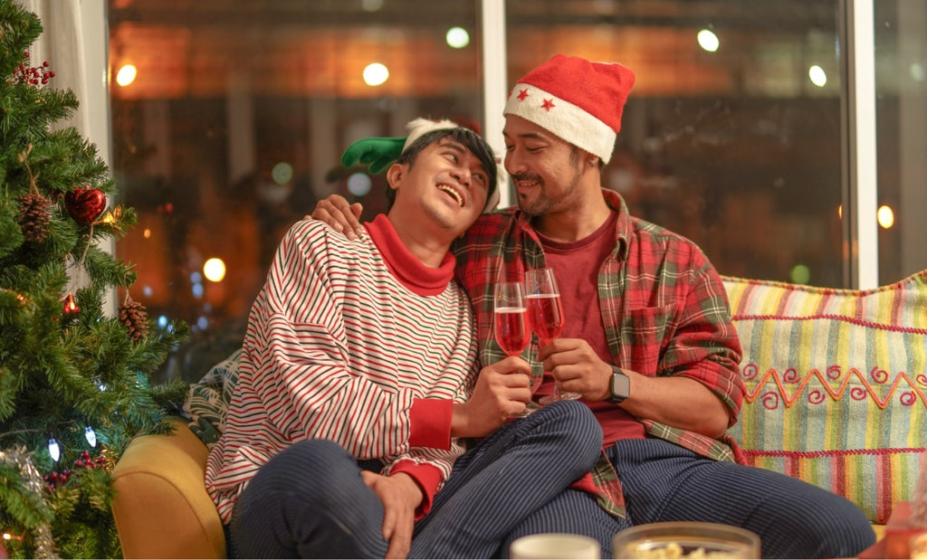 A couple clinks holiday glasses together in a loving manner on the sofa.