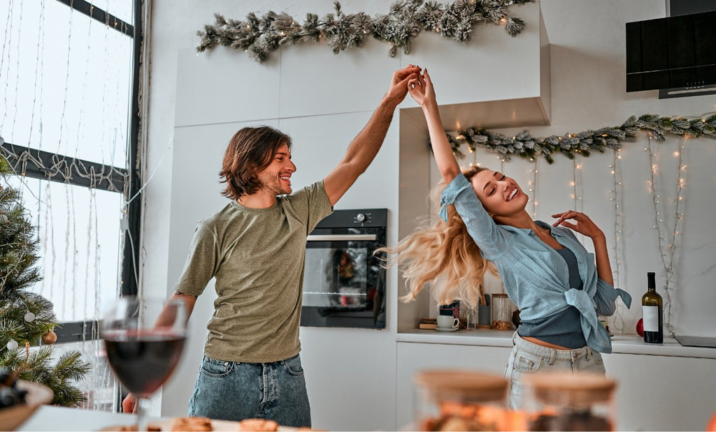 Two people dancing around each other during the holidays in the kitchen.