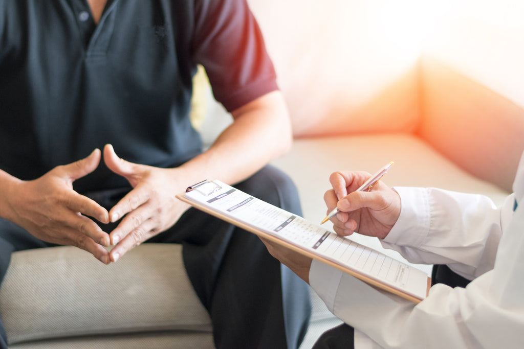 A man consulting his doctor about safe sex and condom effectiveness.