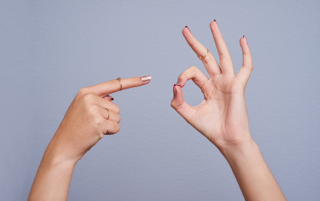 Two hands – one pointing and one making a circle with the thumb and pointer.