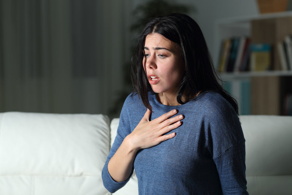 A woman has her hand on her chest while experiencing an allergic reaction.