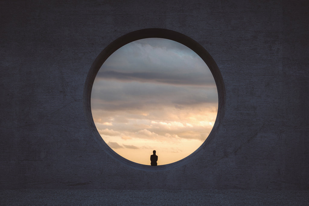 A small silhouette of a person against a circle of cloudy sky.