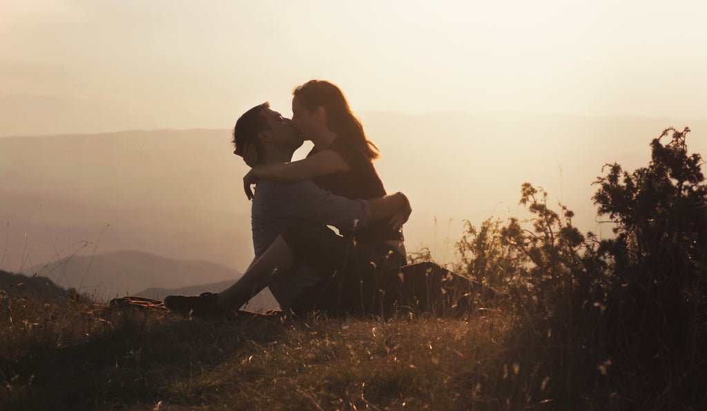 A couple shares an intimate kiss with a beautiful view.