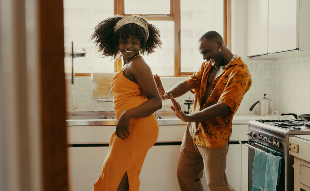 A married couple enjoy dancing with each other in the kitchen, knowing their step on how to improve sex life in marriage starts with some freestyling.