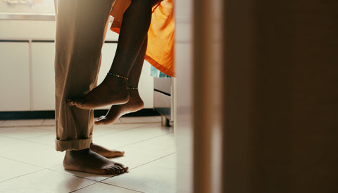 A woman's legs dangling from the counter while her partner stands in front of her.