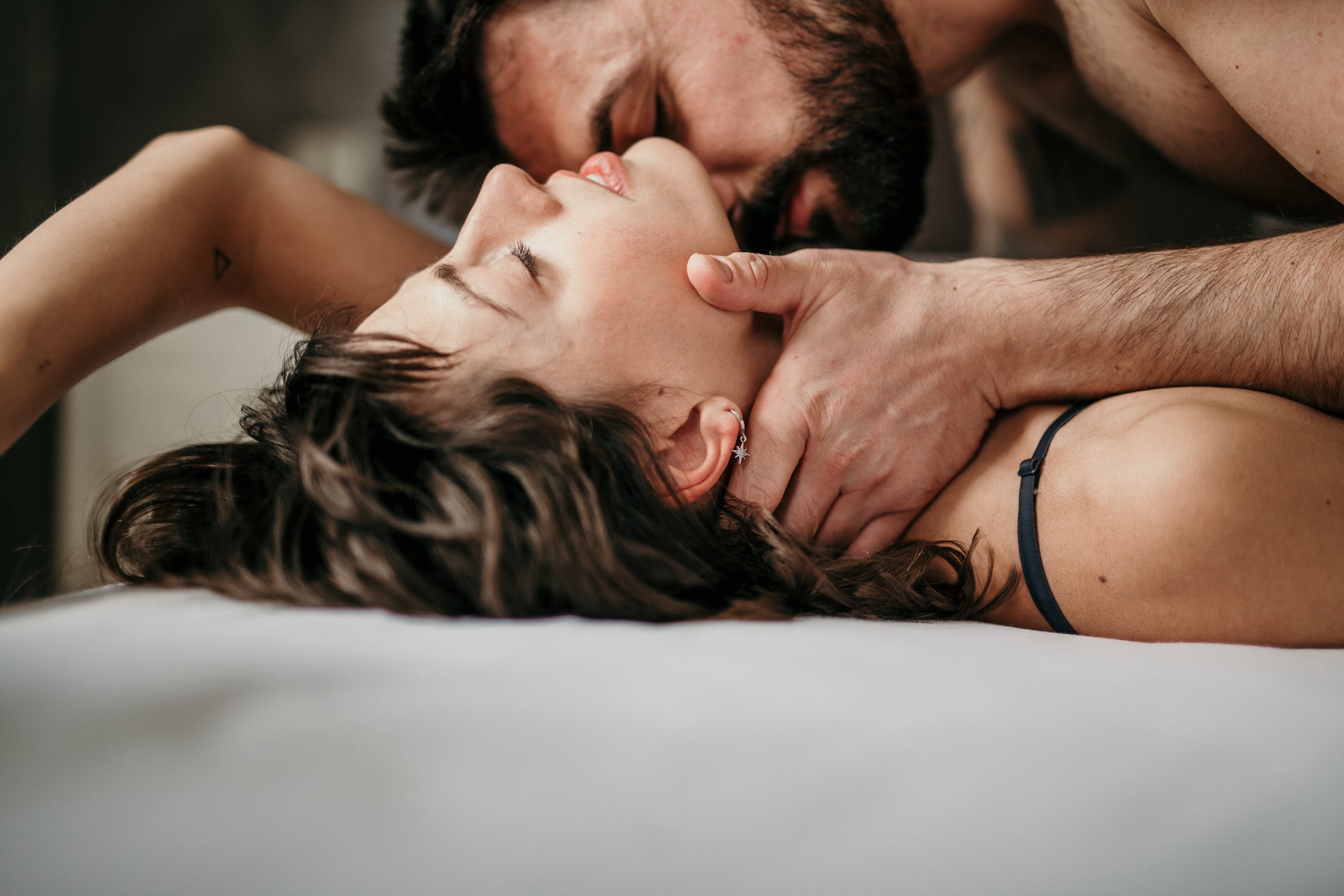Un homme allongé sur une femme dans un lit dans une étreinte passionnée. 