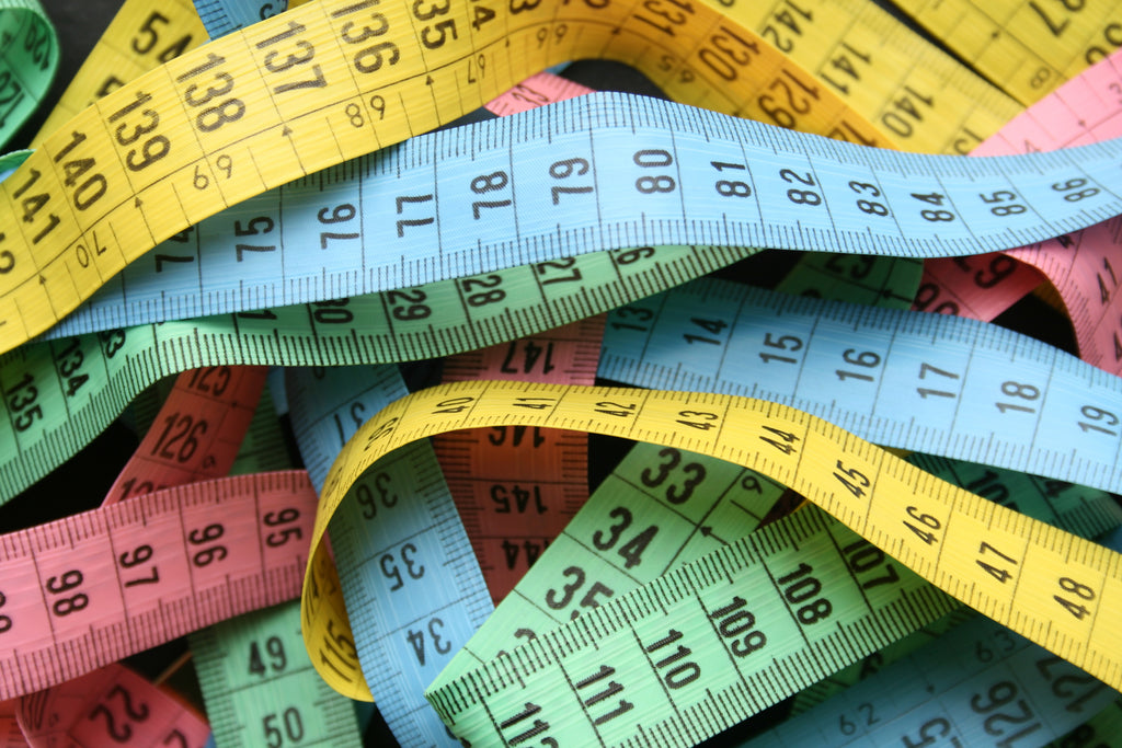 Colourful measuring tapes in a pile.