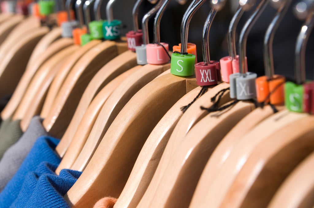A row of wooden clothes hangers with different size labels representing the variety of Durex condom sizes.