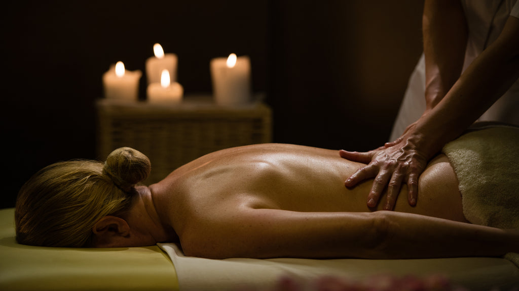 A woman receives a back massage while lying facedown.