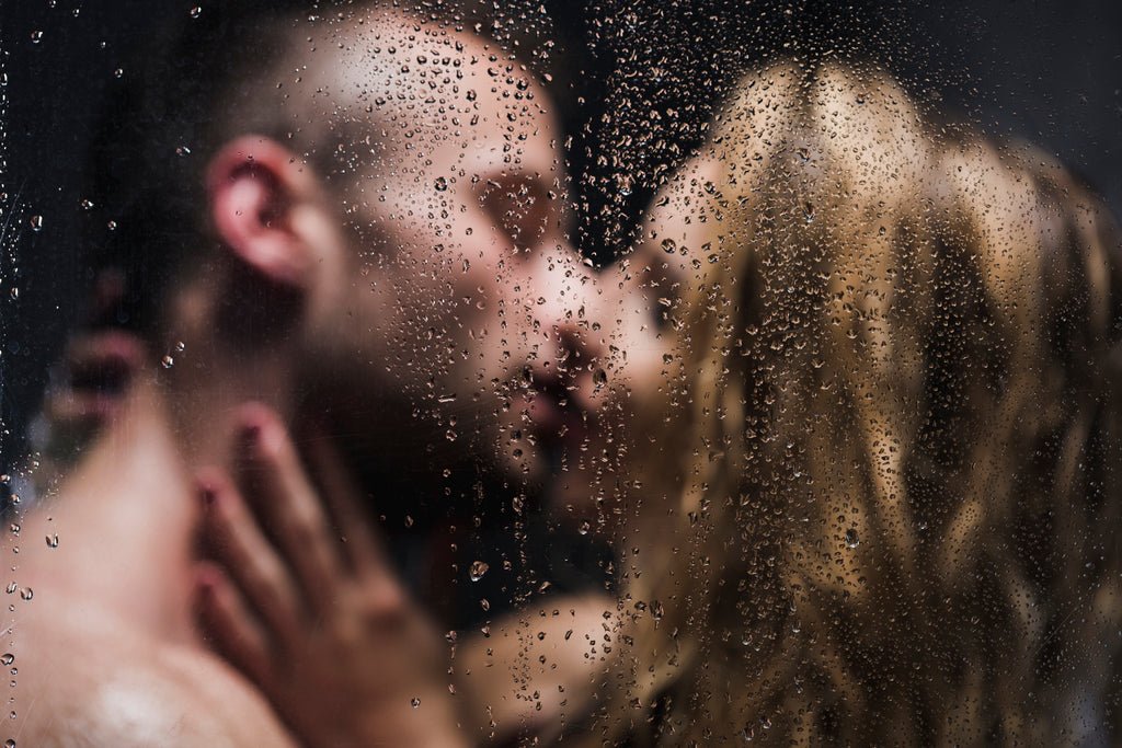 A couple kiss passionately in the shower.