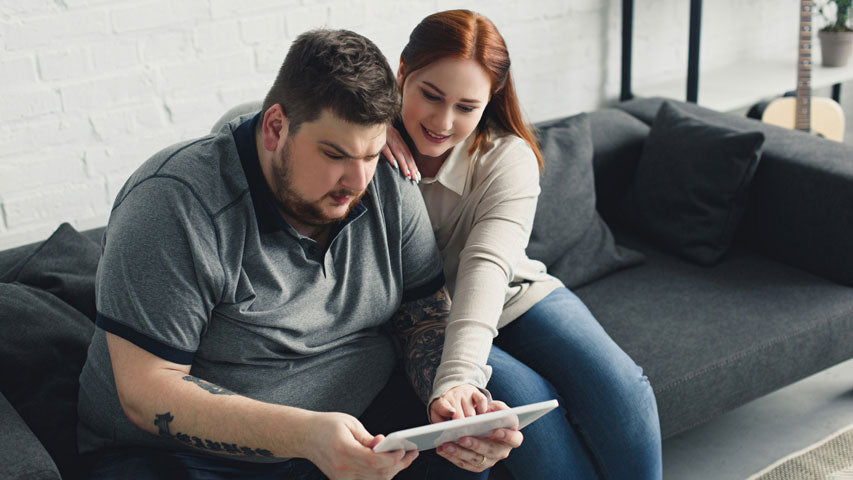 Woman showing her male partner a resource surrounding men’s mental health month on a tablet.