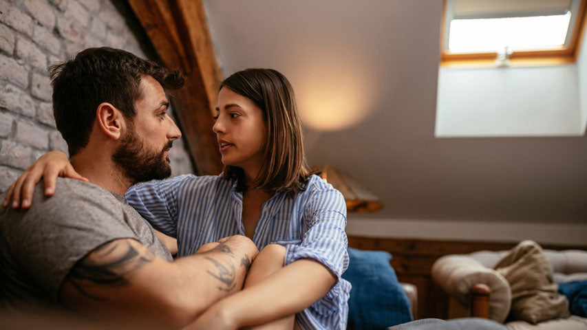 Woman comforting her male partner while talking about men’s mental health month in a room with a sunroof.