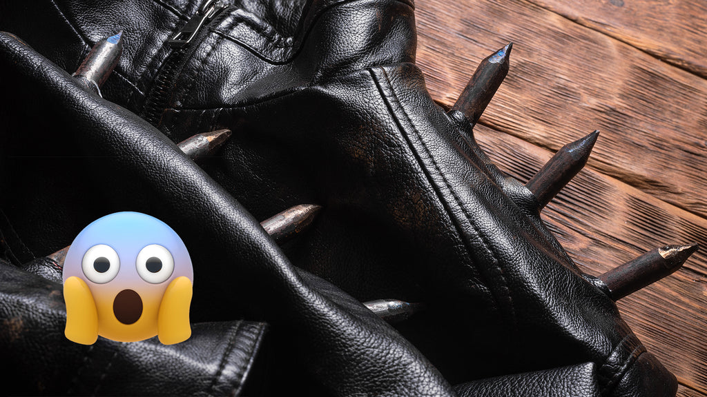 Studded/spiked leather laying on top of wood surface next to a face screaming in fear emoji.