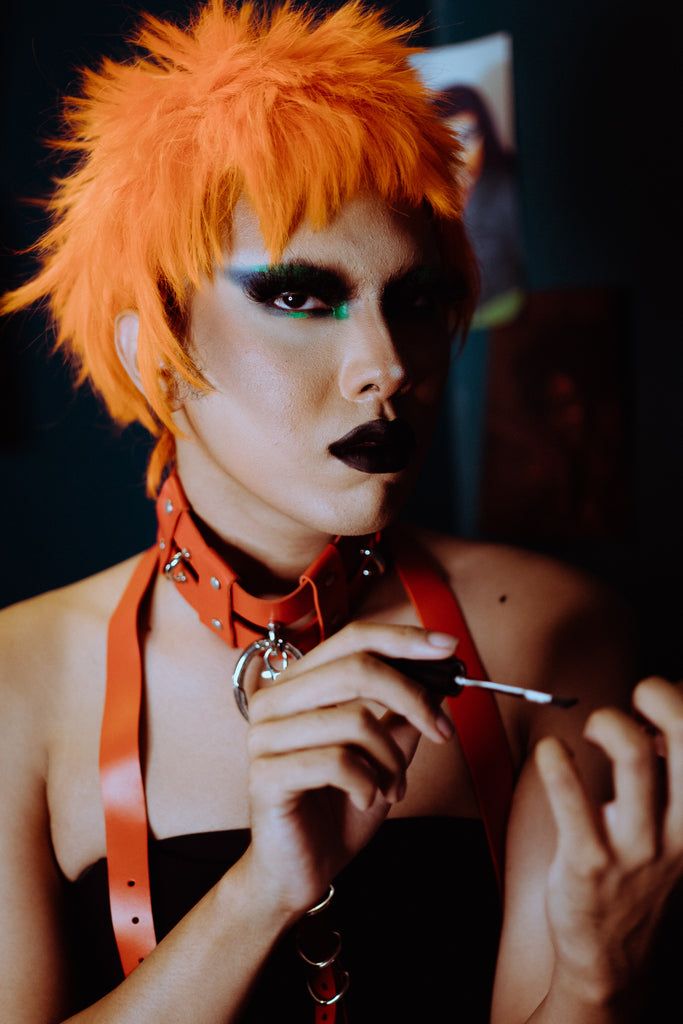 A person with orange hair paints their nails.