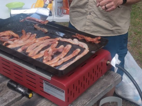 Tocino frito en una plancha para acampar