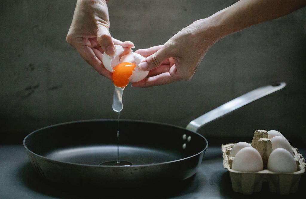 Mujer cocinando huevos en una sartén