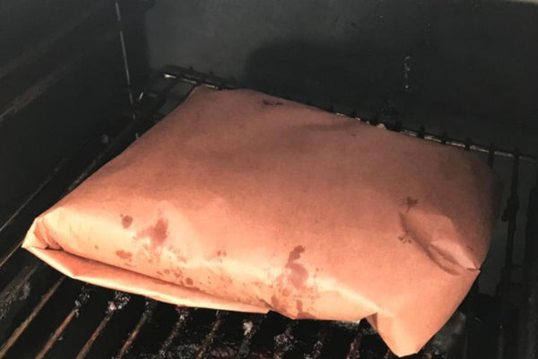 wrapped brisket resting in a smoker