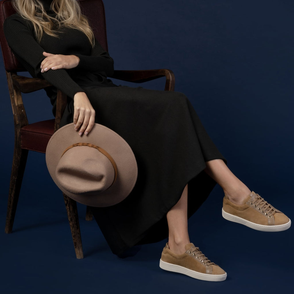 female side seated down with feet shod in beige sneakers caramel small size shoes model from petitfour feeling good collection
