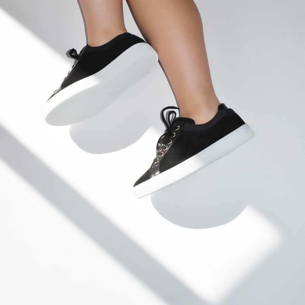 female side legs with feet shod in black sneakers liquorice petite size shoes model from petitfour feeling good collection