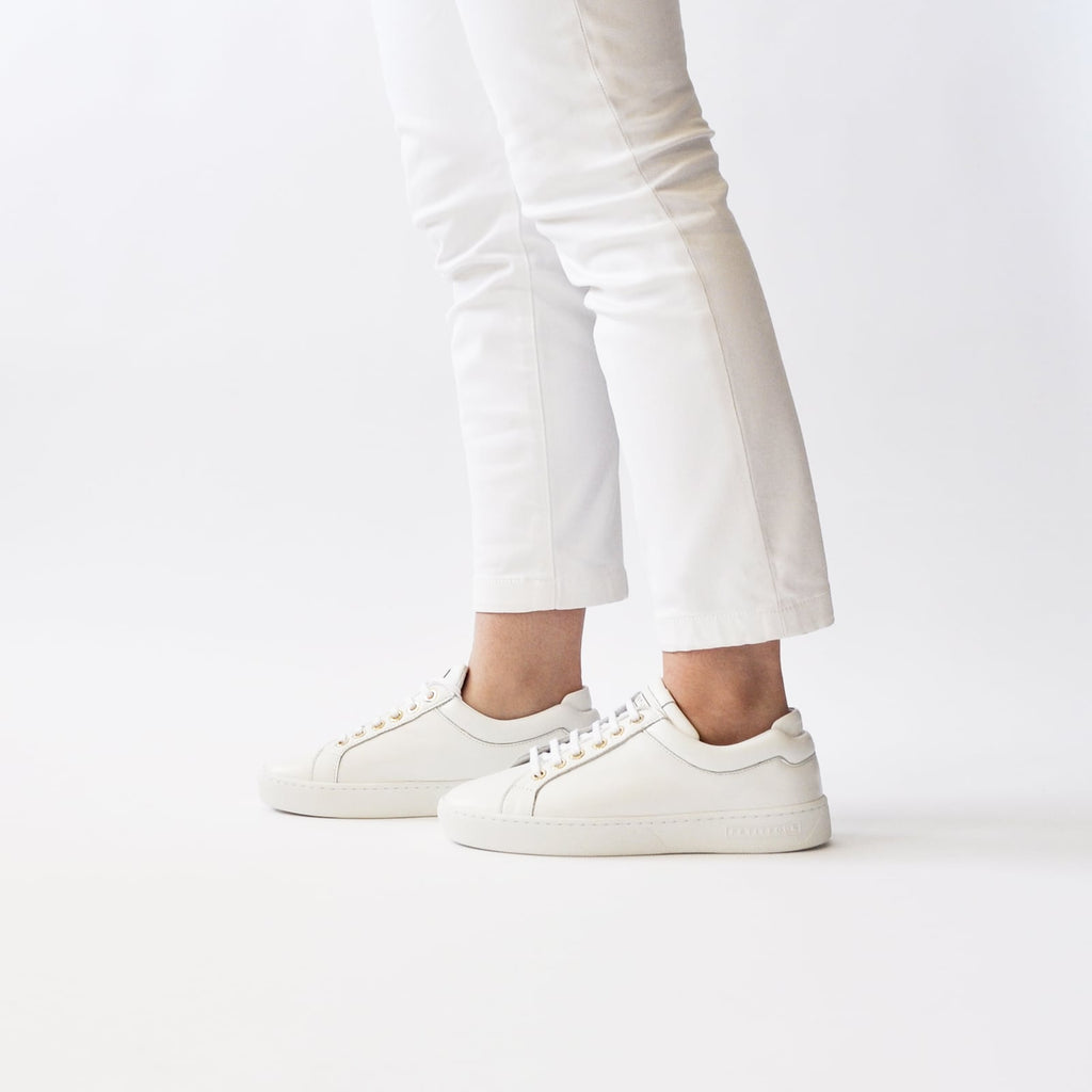 female legs with feet shod in white sneakers marshmallow petite size shoes model from petitfour feeling good collection