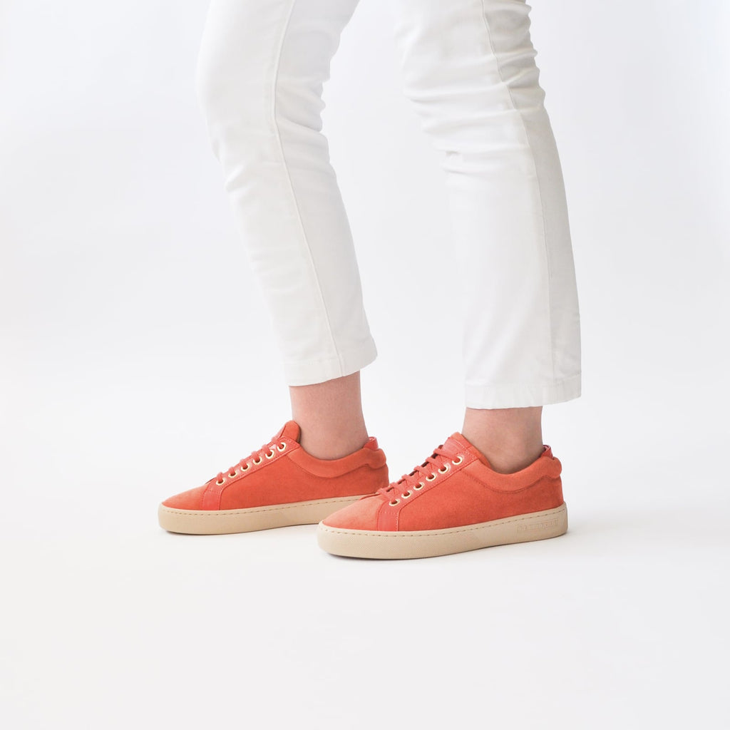 female legs with feet shod in orange sneakers papaya petite size shoes model from petitfour feeling good collection