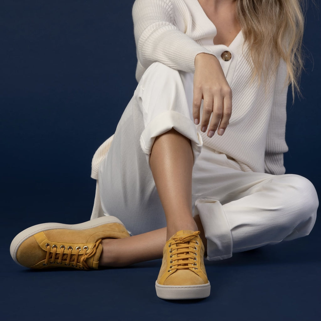 female seated down with feet shod in yellow sneakers saffron small size shoes model from petitfour feeling good collection
