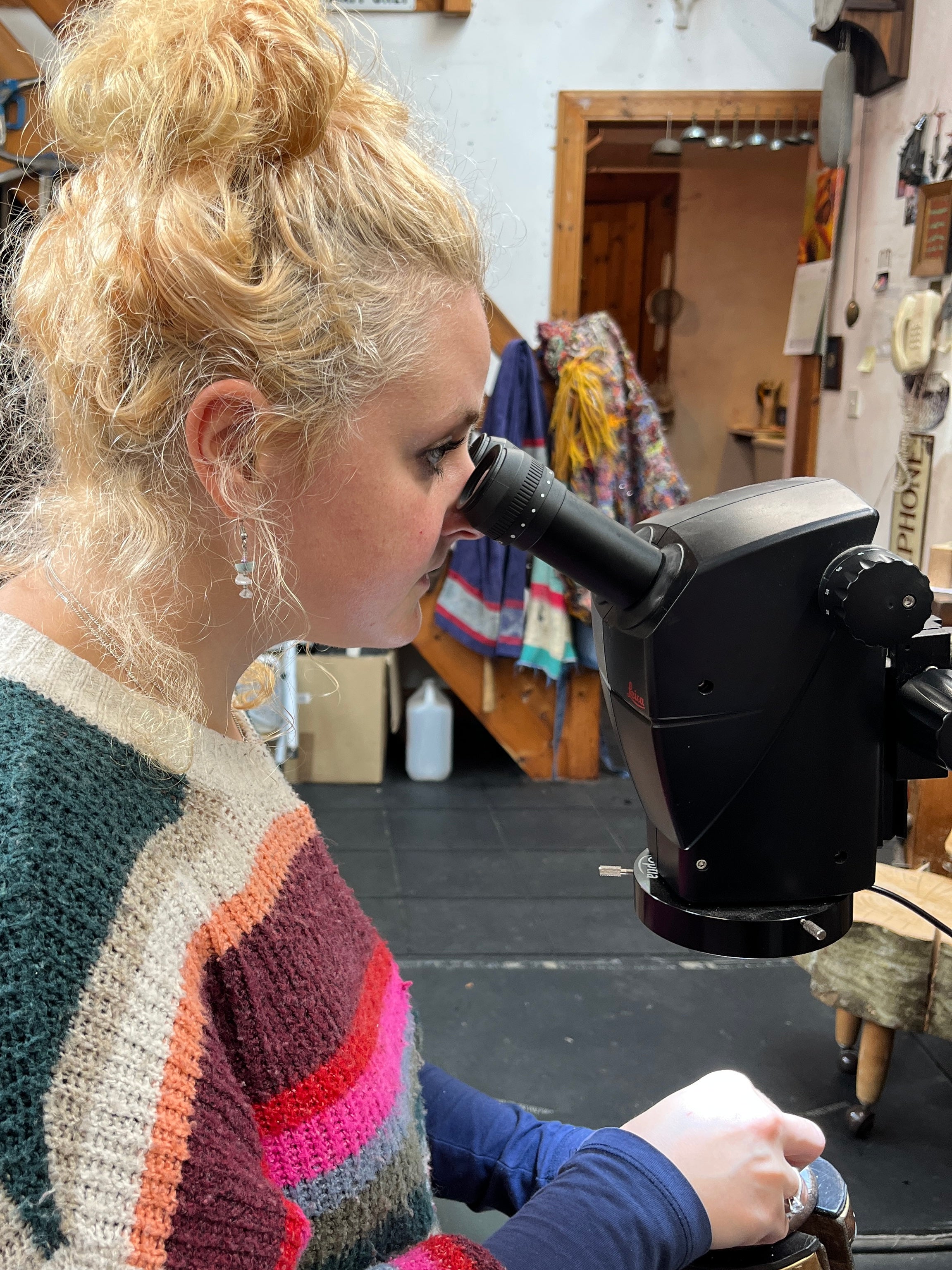 Olivia engraving her silver disc, using a microscope to zoom in on the details