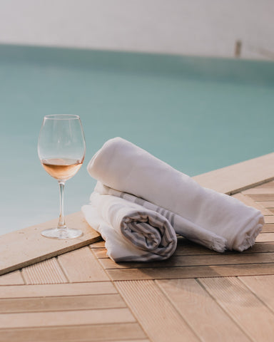 towels and a glass of wine next to a swimming pool