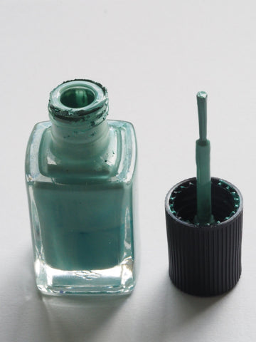 an open bottle of green nail polish