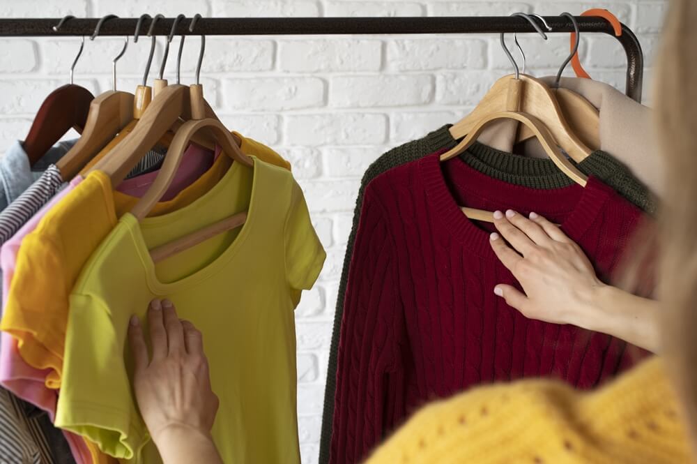 Woman undecided, pondering over which sweatshirt to choose from her wardrobe