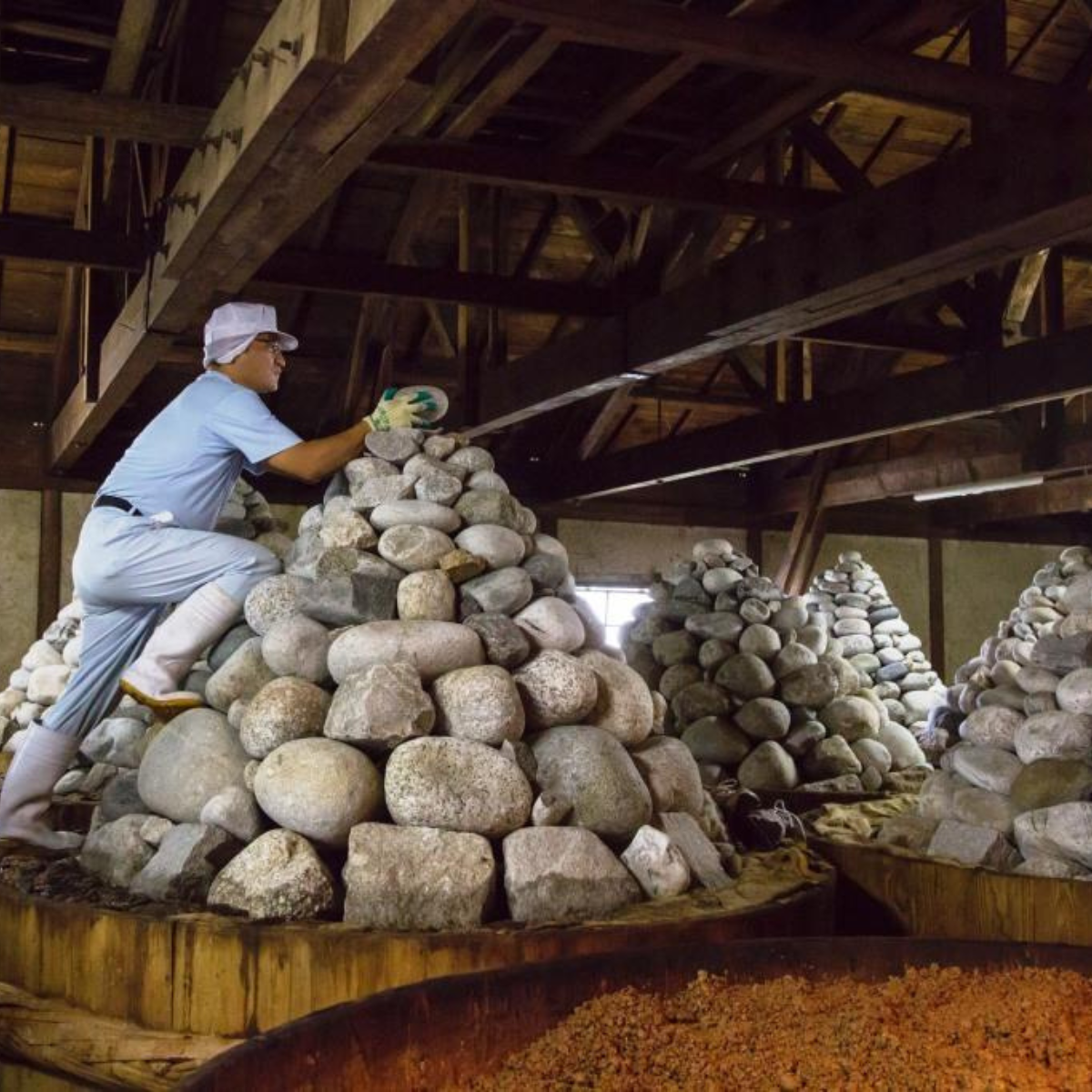 Man puttin stones  on wooden miso barrels