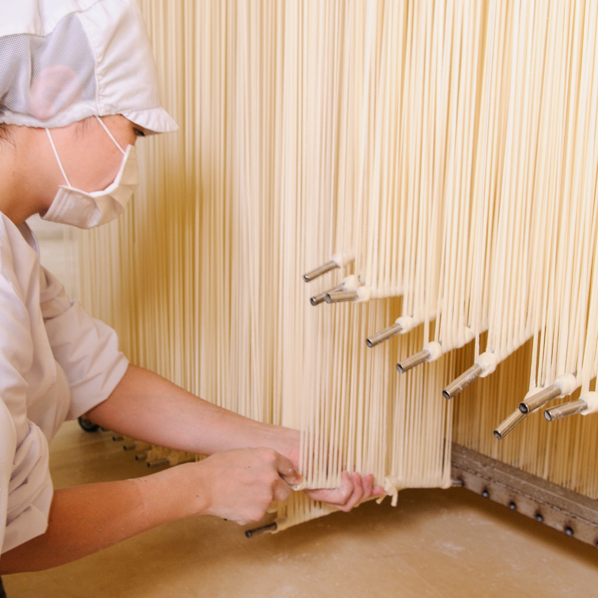 Women stretching inaniwa udon noodles by hand