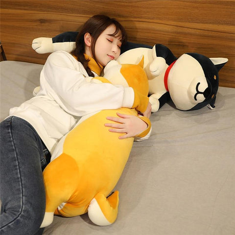 woman laying down hugging a yellow plush and has head on a black shibe plush