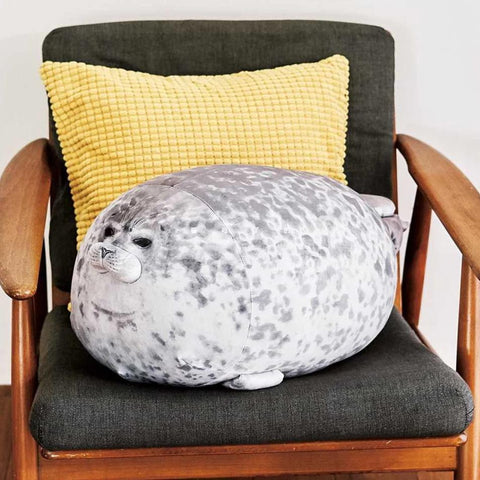 Fat seal plushie on a brown chair with a yellow cushion