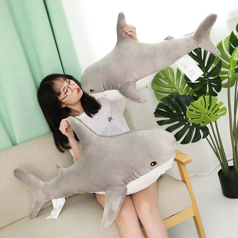 girl playing with two gray cute shark plushies